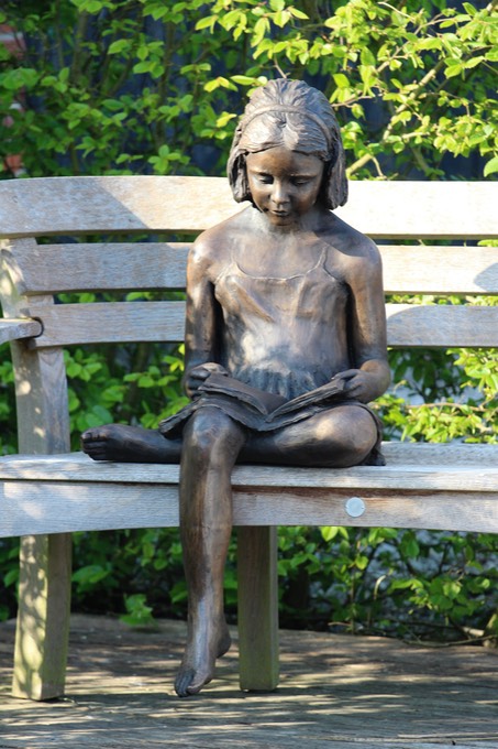 bronze sculpture of girl reading